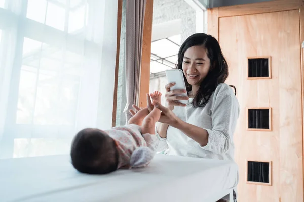 Aziatische moeder nemen een foto pasgeboren baby met smartphone — Stockfoto