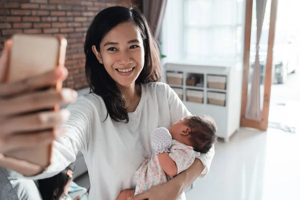 Aziatische jonge moeder glimlach uitvoering pasgeboren baby — Stockfoto