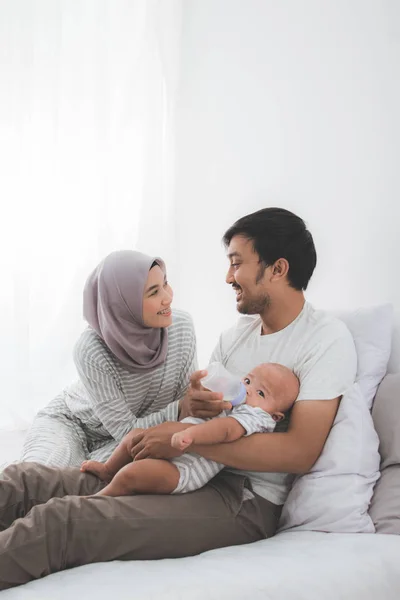 parent feeding their baby boy with bottle of milk