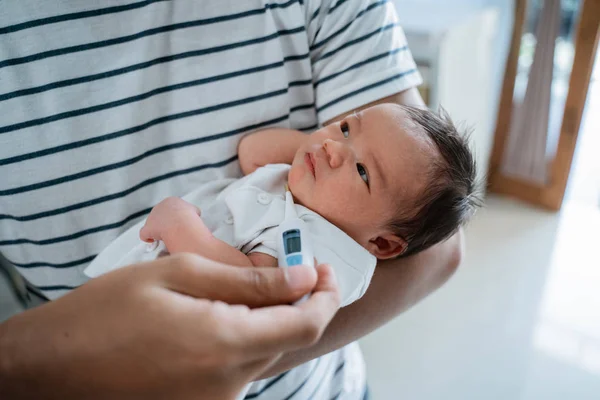 Vader meet de temperatuur naar haar kleine baby — Stockfoto