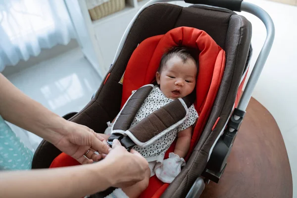 Moeders voorbereiding zet het kleine meisje in een babyzitje — Stockfoto