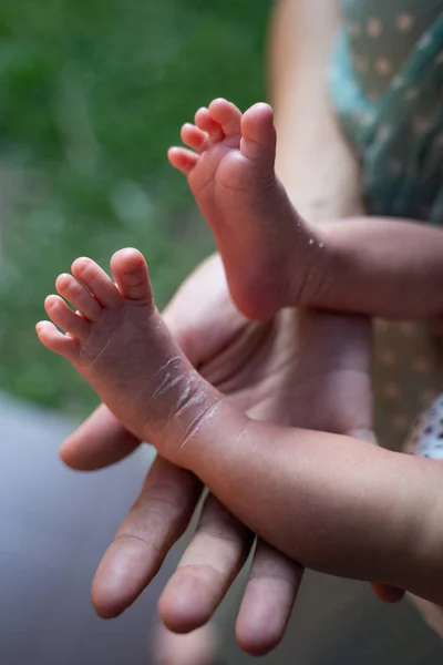 Mãe mãos segurando babys pés pele — Fotografia de Stock