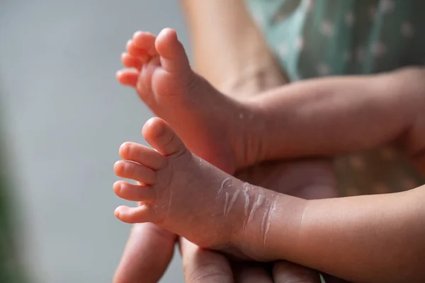 Mains de mère tenant des pieds de bébé — Photo