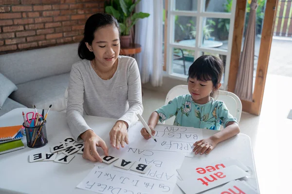mother and daughter learning to read and write letter at home