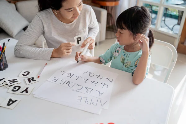 Mother and daughter learning to read and write letter at home — Stock Photo, Image