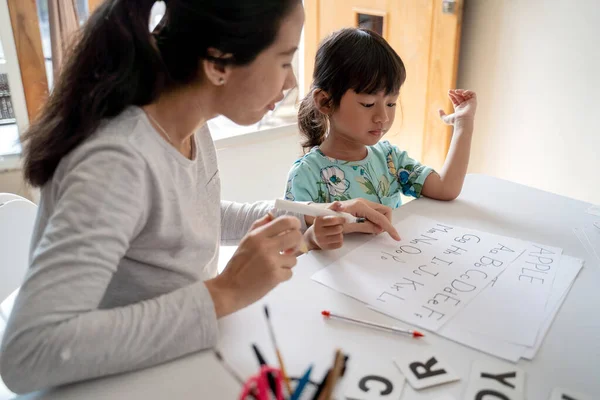 Mother and daughter learning to read and write letter at home — Stock Photo, Image