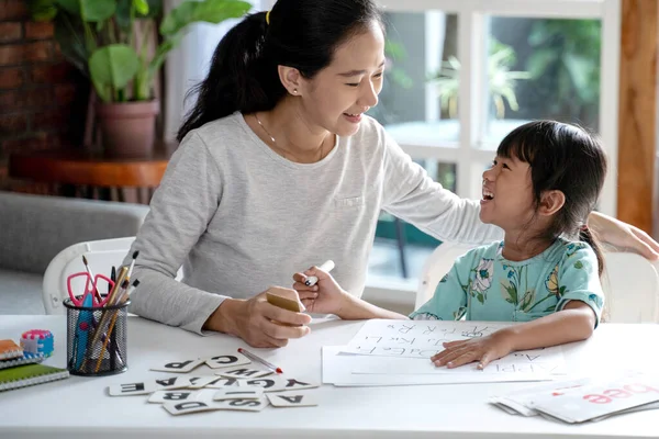 Madre enseñando a su hija lo básico para leer y escribir — Foto de Stock