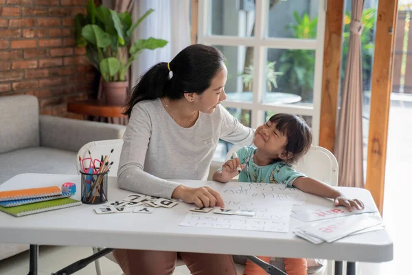 Madre enseñando a su hija lo básico para leer y escribir — Foto de Stock