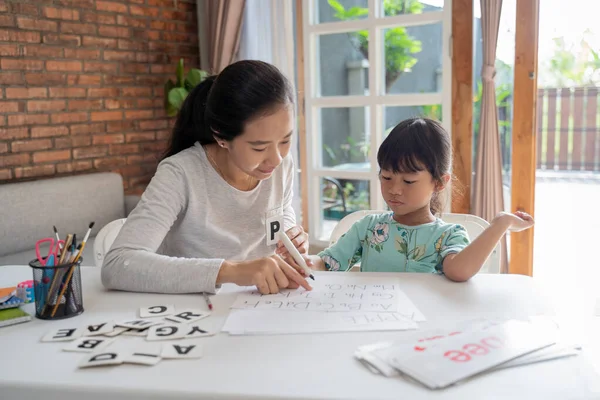Madre enseñando a su hija lo básico para leer y escribir — Foto de Stock