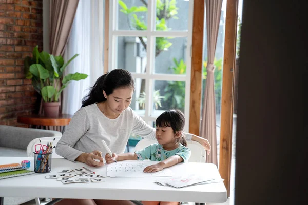 Madre enseñando a su hija lo básico para leer y escribir —  Fotos de Stock