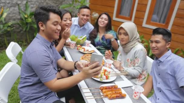 Vrienden barbecue buiten en tonen zijn telefoon — Stockvideo