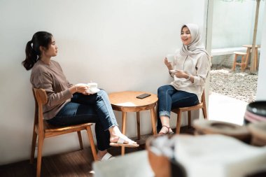 İki arkadaş kafeteryada birlikte kahve içiyorlar.