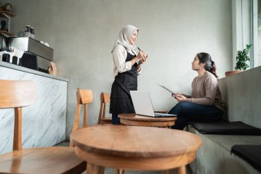 Kadın garson müşteri siparişi yazıyor.