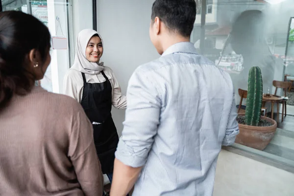 Asiatisk kvinnlig servitör inbjuder gäster att komma in — Stockfoto