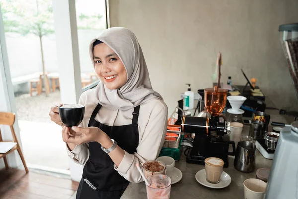 Aziatische gesluierde serveerster glimlachend houd een kopje koffie — Stockfoto