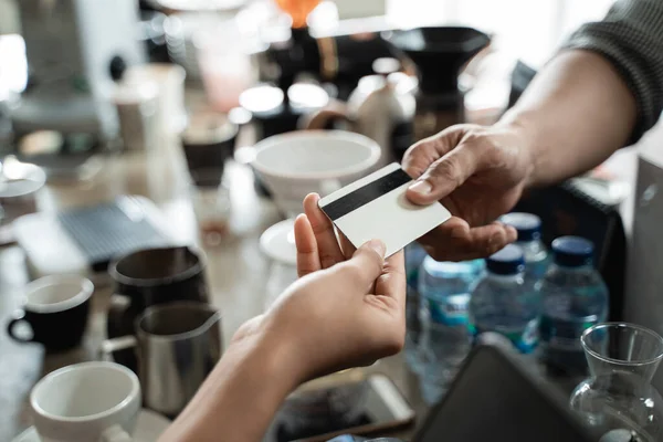 Cerca de la mano del comprador da una tarjeta de crédito al vendedor —  Fotos de Stock