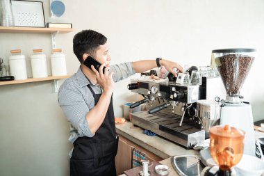 Kahve makinesini kontrol eden barmen.