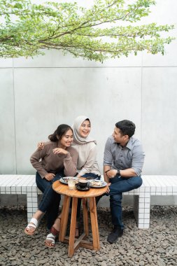 Üç arkadaş kafeteryada birlikte kahve içiyorlar.