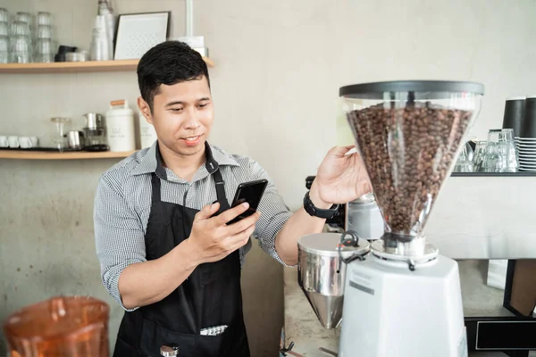 Erkek barista akıllı telefon kullanıyor.
