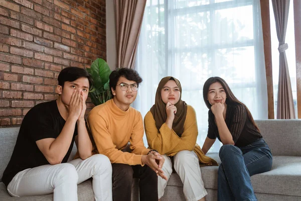 Група молодих азіатів, які сиділи разом на дивані, виглядала розчарованою. — стокове фото