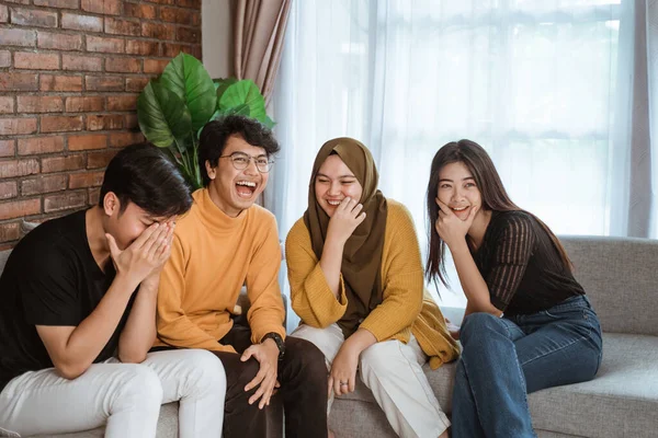 Група азіатських молодих людей сидить разом на дивані сміючись разом — стокове фото