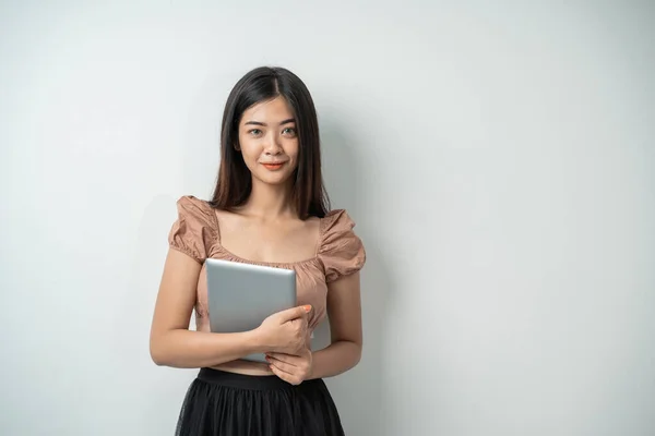 Hermosa chica con el pelo largo sonriendo mientras sostiene una tableta —  Fotos de Stock