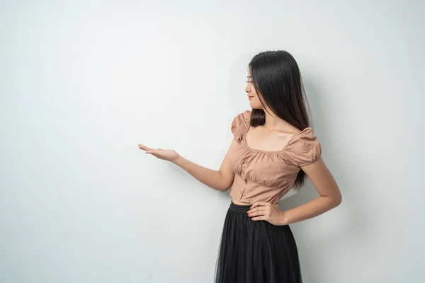Atrakcyjna dziewczyna z długimi włosami na stojąco podczas gestów ręcznych niosących coś przeciwko — Zdjęcie stockowe