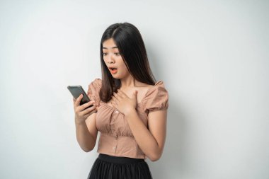 Güzel Asyalı kız ifadesi akıllı bir telefonun ekranını görünce hayrete düştü.