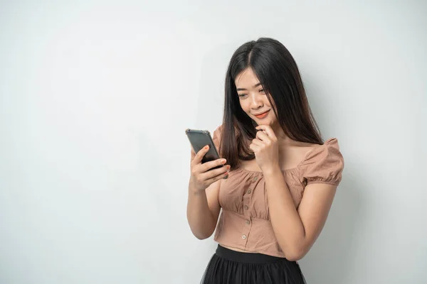 Menina bonita com sorriso de cabelo longo e de pé usando telefone inteligente — Fotografia de Stock