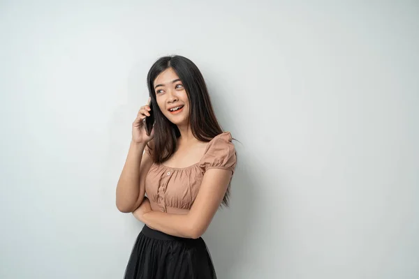 Hezká dívka s dlouhými vlasy úsměv a stojící pomocí chytrého telefonu — Stock fotografie
