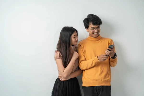 Asijské mladé páry chatování, zatímco stojí na svých chytrých telefonech spolu — Stock fotografie