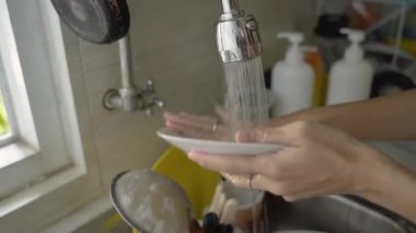 Kadın bulaşık yıkıyor.