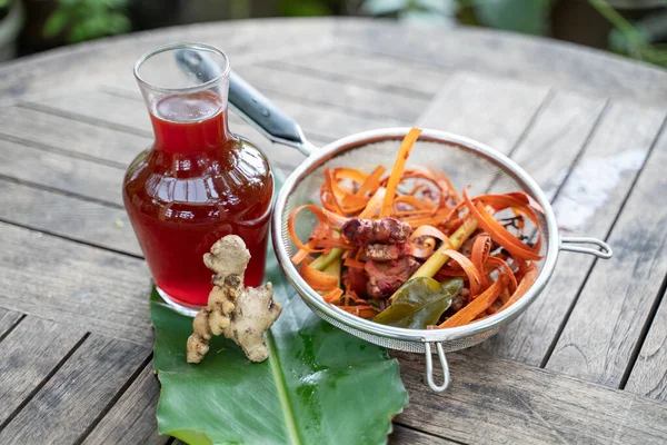 Bevande wedang uwuh in bottiglie di vetro e zenzero rosso, trucioli di legno secang, citronella in setaccio inox — Foto Stock