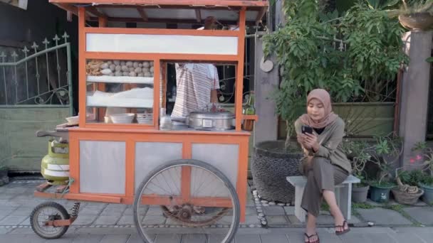 Streetfood-Verkäufer reicht eine Schüssel Bakso — Stockvideo