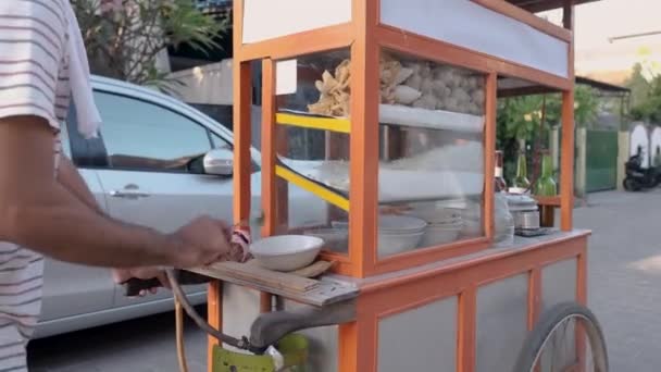 Man selling bakso by walking and pushing down the food carts — Stock Video