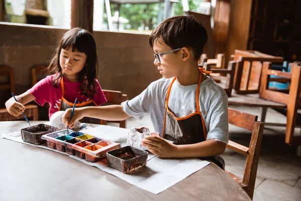 Дети раскрашивают глину кисточками и краской — стоковое фото