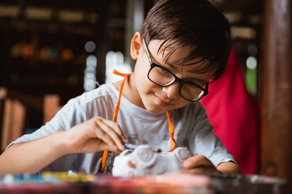 Niño con entusiasmo pinta artesanías de arcilla con pintura — Foto de Stock