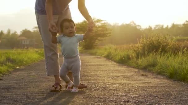 Mor hjälpa sitt barn att gå hennes första steg — Stockvideo