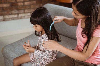 Kardeşinin saçını taramasına yardım eder.