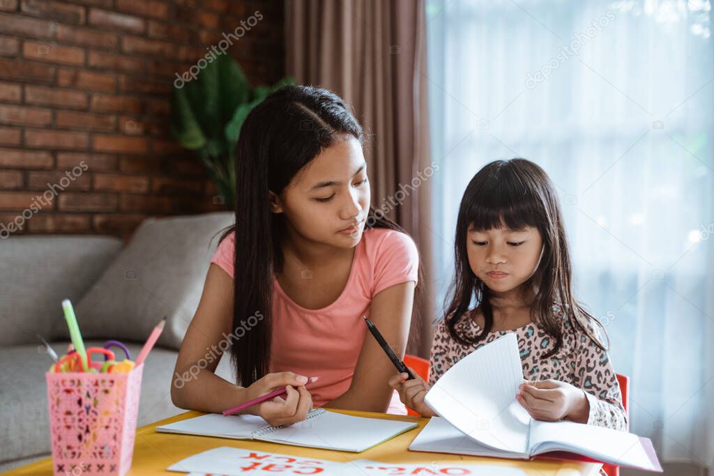 sister help her little sibling to learn and study