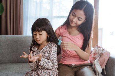 Kardeşinin saçını taramasına yardım eder.