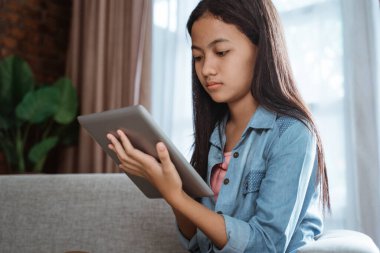 Evde tablet kullanan ciddi görünümlü bir genç.