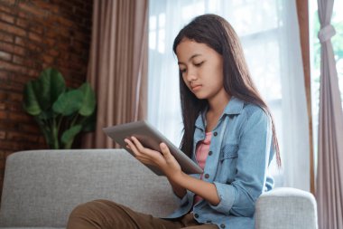 Evde tablet kullanan ciddi görünümlü bir genç.