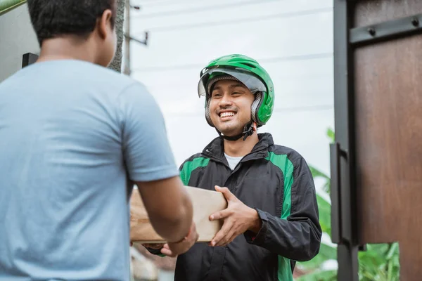 Mensajero masculino con casco entrega paquete al cliente —  Fotos de Stock