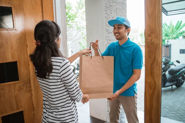 Entrega sorrindo para a mulher enquanto segurando saco de compras — Fotografia de Stock