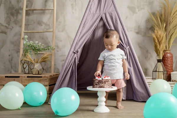 Asiático menino pega cerejas em um bolo de aniversário — Fotografia de Stock