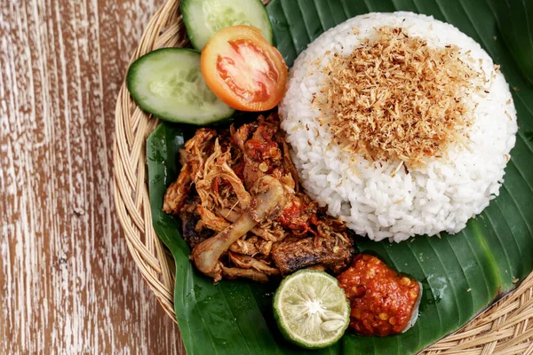 Close up de ayam geprek com arroz branco e fatias de tomate, pepino, limão e sambal — Fotografia de Stock