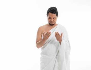 Müslüman adam geleneksel beyaz giysiler içinde dua ediyor.