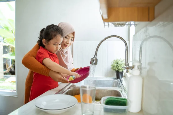 Bambina aiuto suo madre in lavaggio piatti — Foto Stock