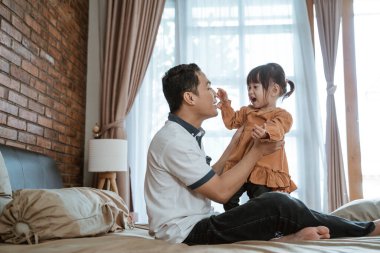 Küçük kız babasının burnunu tutarken mutlu bir şekilde güldü.